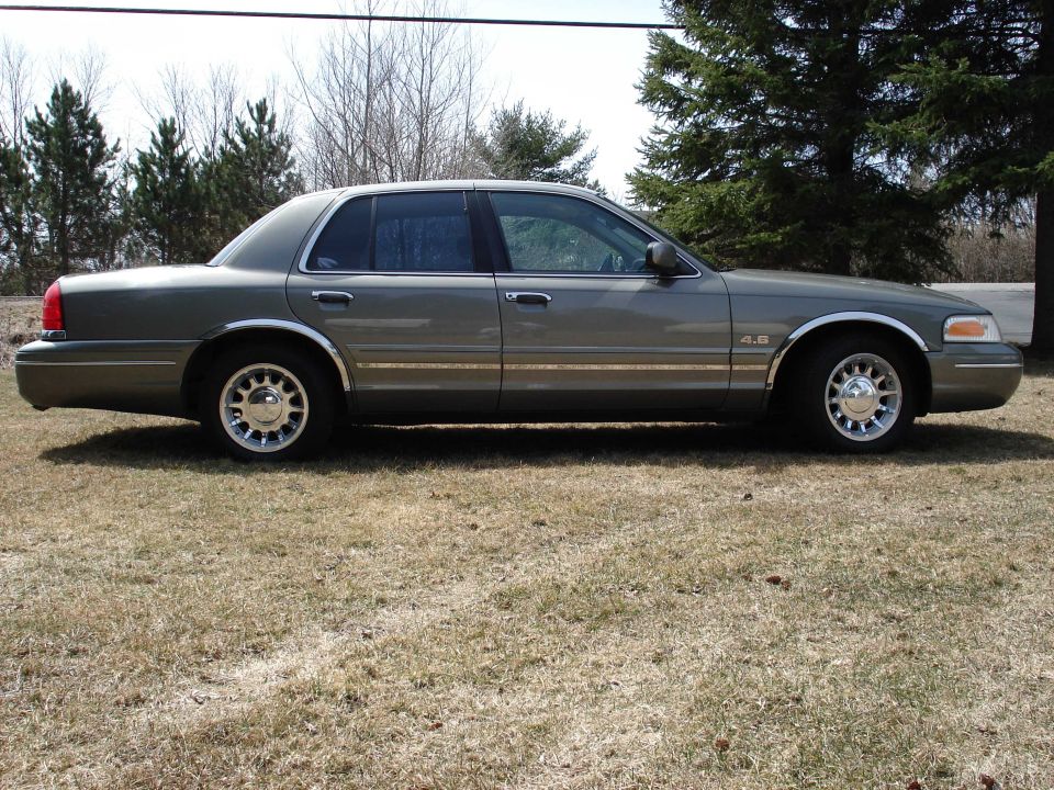 Gray four-door sedan with 4.6 badge parked on grass
