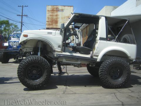 1987 Suzuki Samurai - A modified white Suzuki Samurai sits outside with another vehicle in the background.