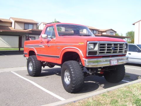1986 Ford Bronco - This lifted 1986 Ford Bronco features a bright red exterior and prominent off-road tires.