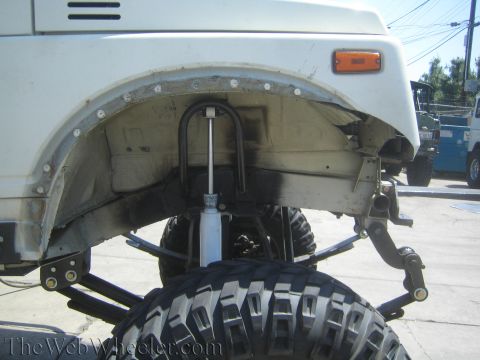 1987 Suzuki Samurai - Close-up view of the front suspension system of a Suzuki Samurai, highlighting modifications to the shock absorber setup.
