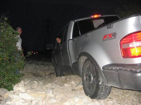1979 Ford Bronco - Silver pickup truck with FX4 Off Road decal navigating rocky terrain at night.