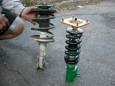 1990 Ford Probe - A side-by-side comparison shows a worn-out suspension strut next to a newly installed green and black coilover assembly.