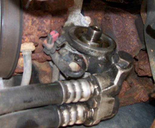 Oil filter housing with hoses and rusty engine components