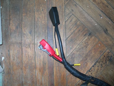 1992 Ford Taurus - Close-up of automotive battery cables, a red clamp and a black connector, laid out on a wooden floor.