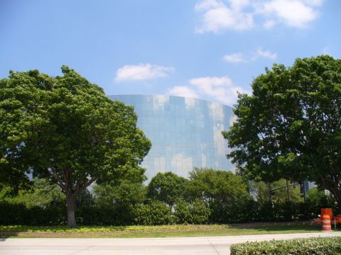 1992 Ford Bronco - Glass building and trees under a blue sky with clouds. Supermotors.net watermark visible.