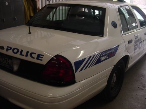 2002 Ford Crown Victoria - Rear view of a white Ford Crown Victoria police car with 'POLICE' markings and emergency dial graphics.