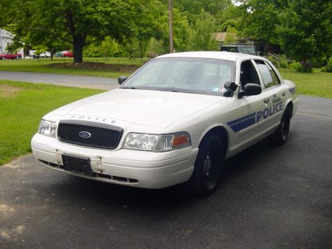 2002 Ford Crown Victoria - White 2002 Ford Crown Victoria police car parked on asphalt, showing front 3/4 view with 'POLICE' markings.