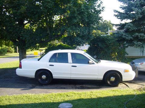 2002 Ford Crown Victoria - Side profile of a white 2002 Ford Crown Victoria sedan with black wheels.