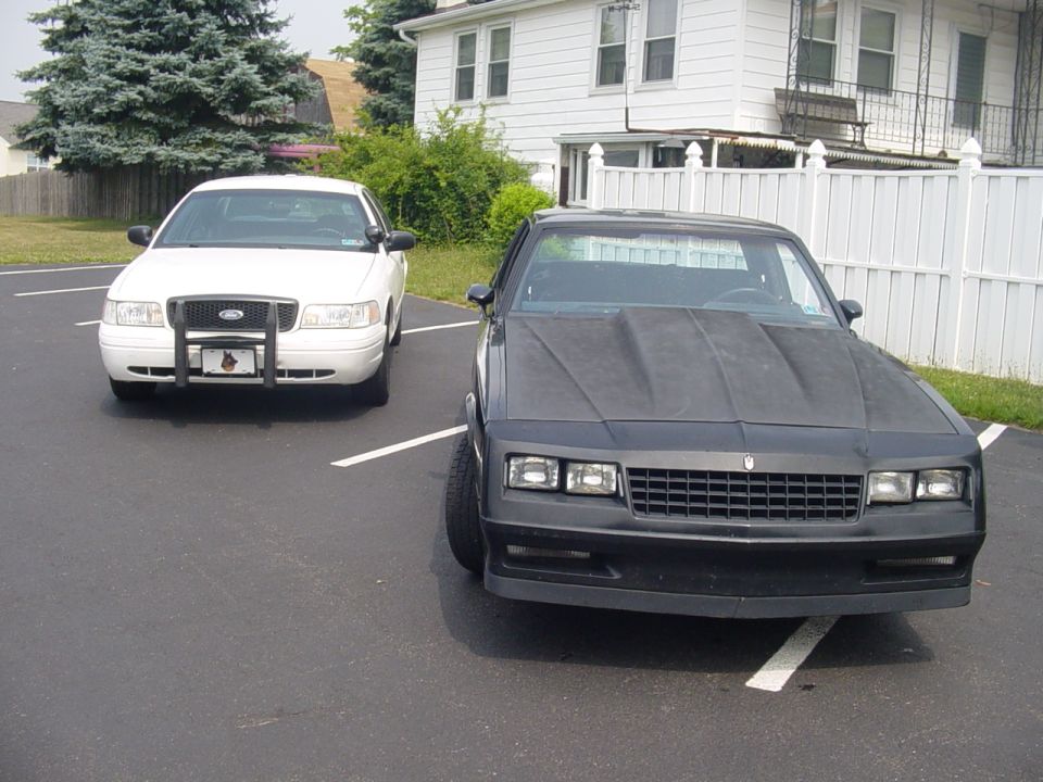 Black Chevrolet Monte Carlo SS beside a white Ford Crown Victoria in a lot