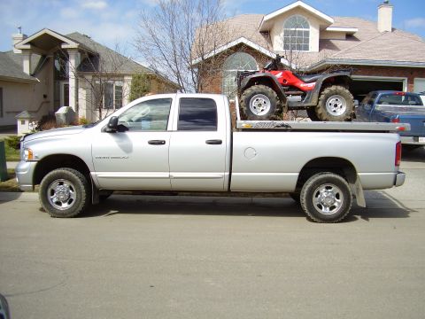 2005 Dodge 3500 - A silver 2005 Dodge 3500 pickup truck is seen from the side, transporting an ATV on its flatbed.