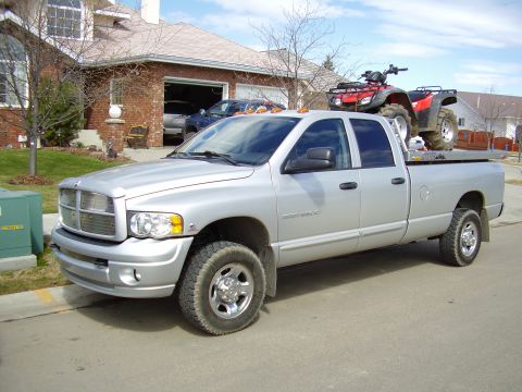2005 Dodge 3500 - Silver 2005 Dodge 3500 pickup truck with an ATV in the bed, parked in front of a residential house.