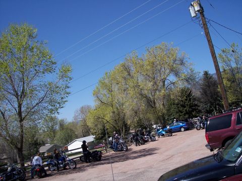 1972 Ford Ranchero - A collection of motorcycles and cars are parked in an outdoor lot under a clear blue sky.
