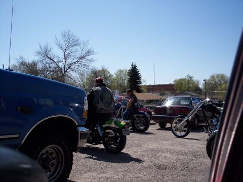 1972 Ford Ranchero - Several motorcycles and a blue truck are parked in an outdoor lot under a clear blue sky.
