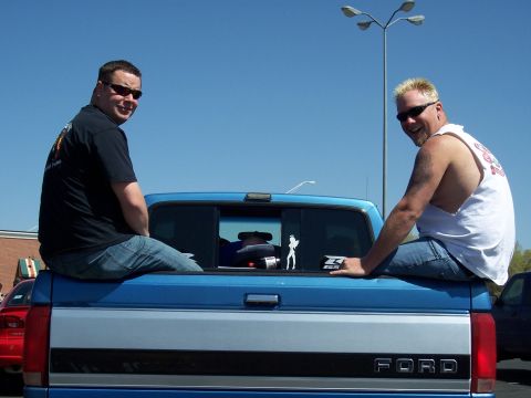 1972 Ford Ranchero - Two men relax on the tailgate of a blue Ford pickup truck under a clear blue sky.