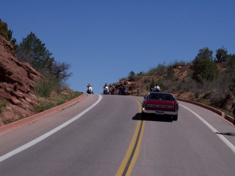 1972 Ford Ranchero - A red 1972 Ford Ranchero is seen from behind on a winding road, with several motorcycles in front.