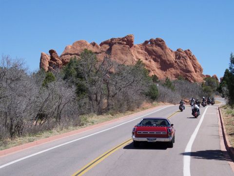 1972 Ford Ranchero - A convoy of motorcycles follows a red car on a scenic road with distinctive red rock formations.
