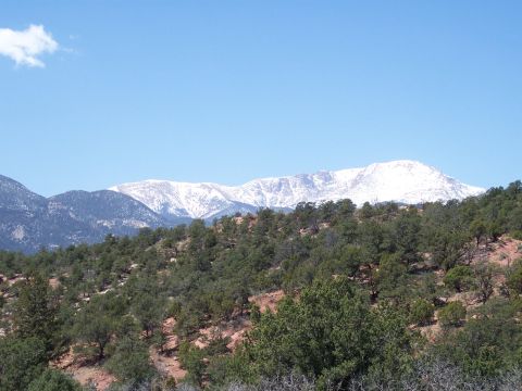 1972 Ford Ranchero - A vast mountain landscape under a bright blue sky, with snow on the peaks and trees in the foreground.