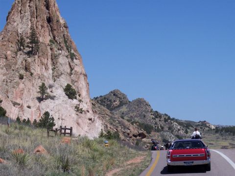 1972 Ford Ranchero - A red car and motorcycles travel along a scenic road with large rock formations.