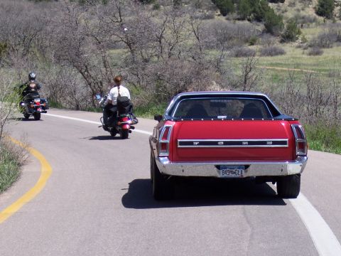 1972 Ford Ranchero - A red 1972 Ford Ranchero is seen from behind on a winding road, with two motorcycles following.