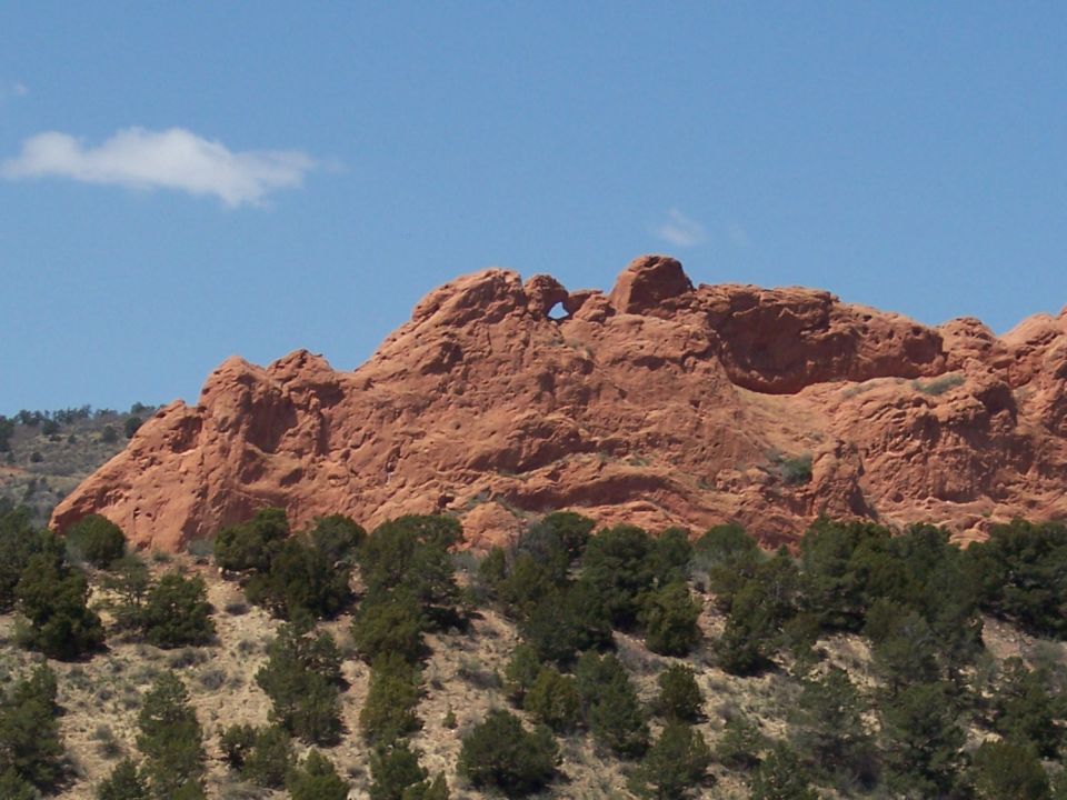 Red rock formation with a natural arch against a blue sky