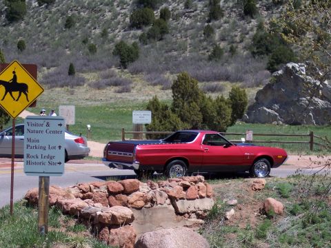 1972 Ford Ranchero - A red 1972 Ford Ranchero is parked near a road with informational signs.