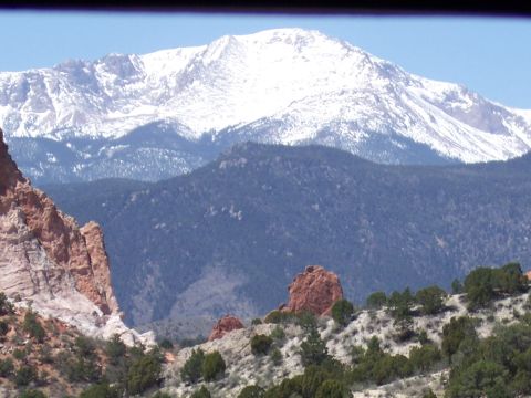 1972 Ford Ranchero - A scenic view of a snow-covered mountain peak overlooking a forest and distinctive red rock formations under a clear blue sky.