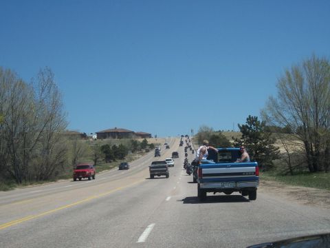 1972 Ford Ranchero - A convoy of vehicles, including motorcycles and cars, travels down a highway on a clear day.