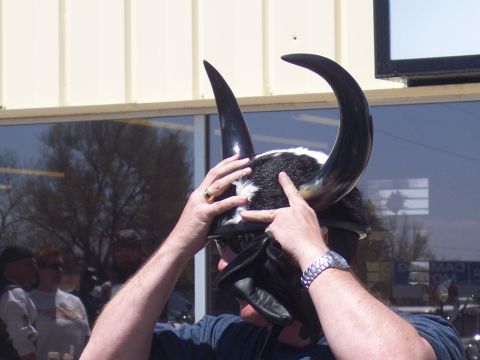 1972 Ford Ranchero - A person adjusts a unique horned helmet, with other people and a building in the background.