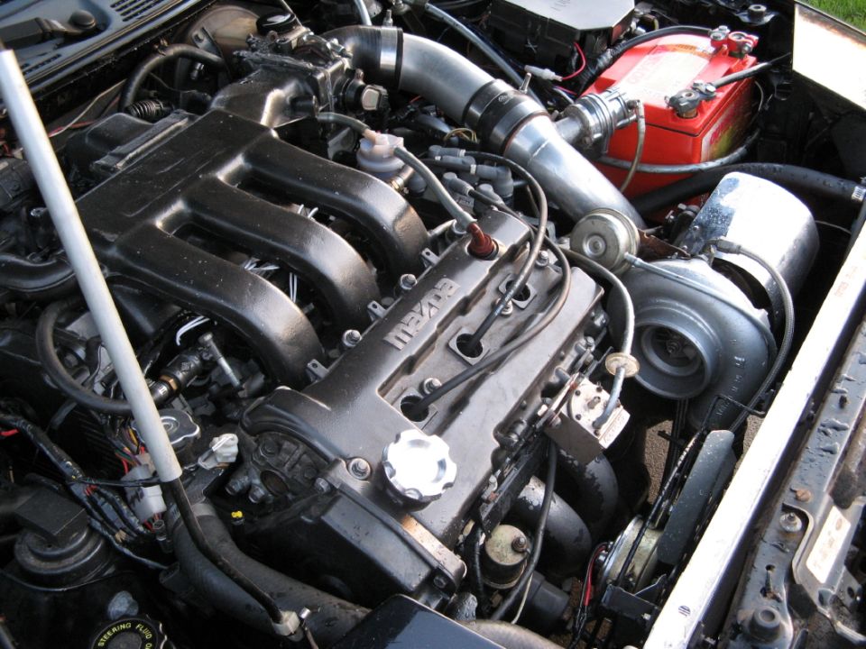 Mazda engine with turbocharger, intercooler piping, and red battery