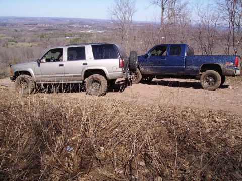 2000 Chevrolet Tahoe - Two trucks are parked on a dirt path overlooking a valley.