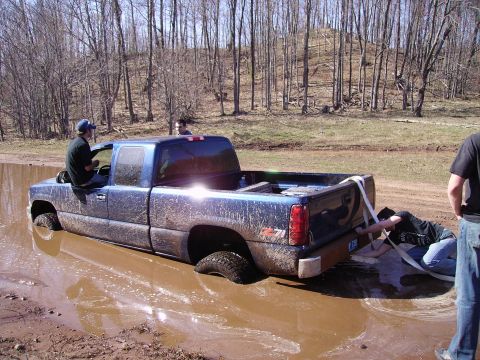 2000 Chevrolet Tahoe - Pickup truck stuck in mud pit with people attempting recovery.