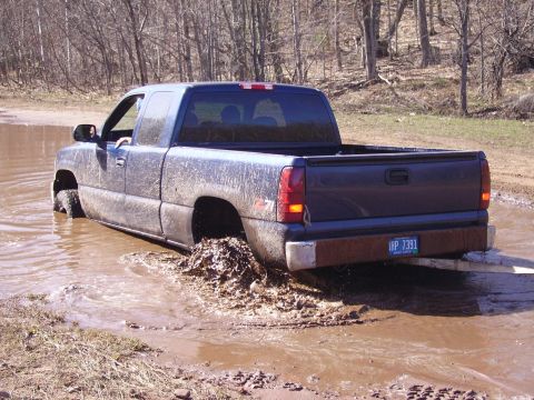 2000 Chevrolet Tahoe - This pickup truck is stuck in a muddy puddle, with its rear tires churning up mud.