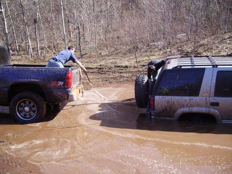 2000 Chevrolet Tahoe - Two SUVs are stuck in the mud, with one person attempting to tow the other out.