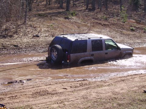 2000 Chevrolet Tahoe - This silver SUV is stuck deep in the mud, with its spare tire visible on the back.