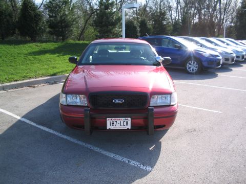 2001 Ford Crown Victoria - A red 2001 Ford Crown Victoria is parked in a lot with other vehicles.