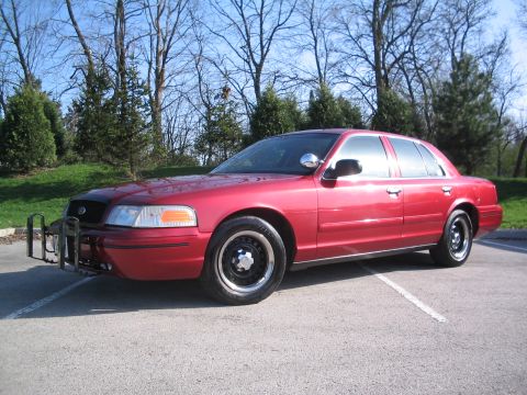2001 Ford Crown Victoria - This red 2001 Ford Crown Victoria is equipped with a front push bumper and parked in a lot.