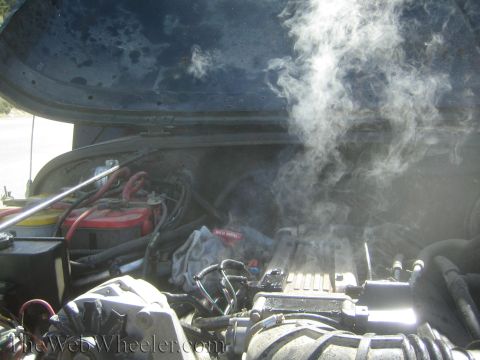 1987 Suzuki Samurai - Steam billows from the engine compartment of a vehicle.