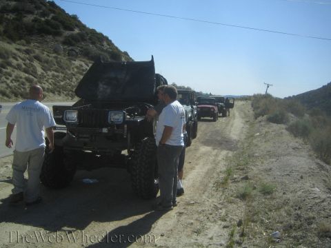 1987 Suzuki Samurai - A group of off-road vehicles are parked on a dirt road, with several people gathered near the lead vehicle.
