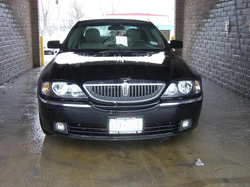 Front view of black Lincoln LS sedan parked in a brick garage bay with wet floor