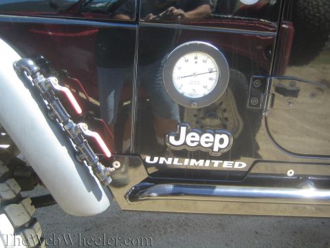 1987 Suzuki Samurai - A black Jeep Unlimited is shown from the side, a gauge and custom plumbing modifications.