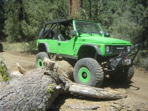 1987 Suzuki Samurai - Modified 1987 Suzuki Samurai tackling an obstacle on a wooded trail.