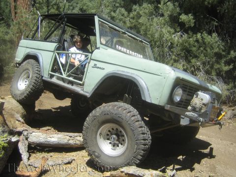 1987 Suzuki Samurai - This modified Ford Bronco is navigating a challenging off-road course with a young driver at the wheel.