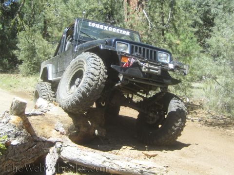 1987 Suzuki Samurai - This modified Jeep Wrangler is navigating an obstacle on a dirt trail, demonstrating its off-road capabilities.
