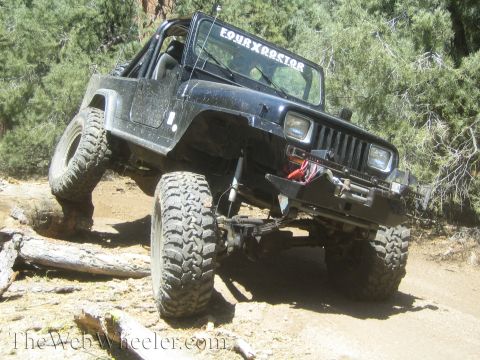 1987 Suzuki Samurai - This modified Jeep Wrangler is navigating a challenging off-road obstacle course with large tires and a lifted suspension.