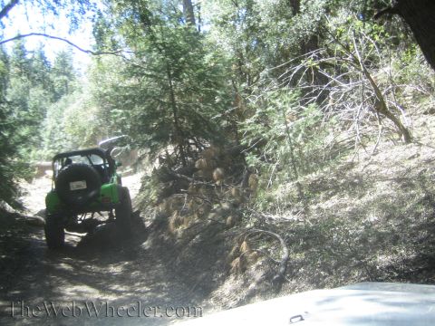 1987 Suzuki Samurai - A green 1987 Suzuki Samurai navigates a wooded trail, with another vehicle visible in the foreground.