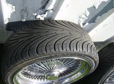 1996 Ford Probe - Close-up of custom wire wheels and performance tires, with a weathered background.