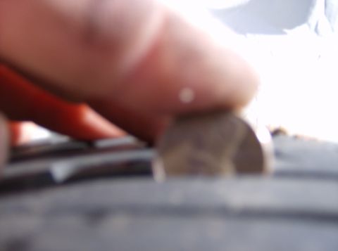 1996 Ford Probe - A finger and a coin are placed on the tread of a tire.