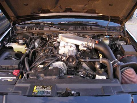 1998 Ford Crown Victoria - Engine bay of a 1998 Ford Crown Victoria, modified with a prominent supercharger and aftermarket air intake.