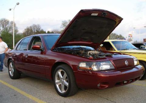 1998 Ford Crown Victoria - Maroon sedan with hood open, parked next to a yellow vehicle. The front 3/4 view highlights the engine compartment.