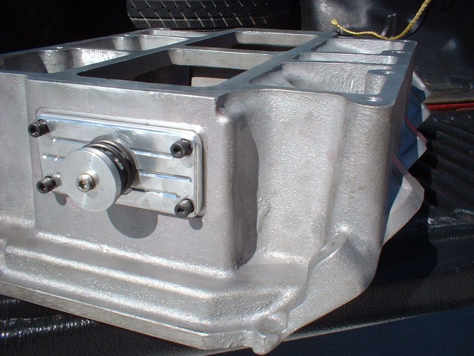 Bare aluminum supercharger case with billet front cover and drive snout, sitting in a truck bed